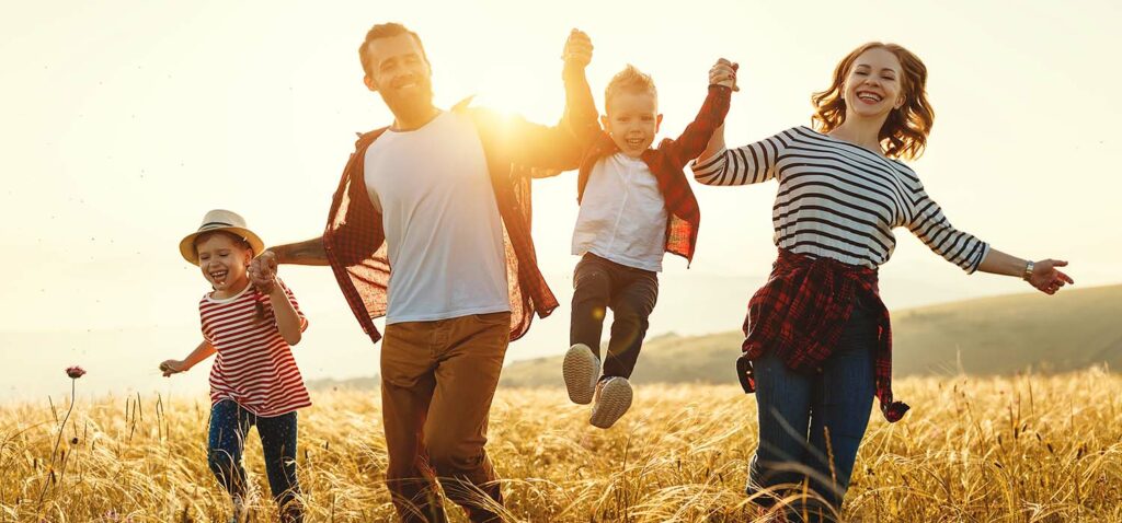 Checklist voyage : une famille heureuse qui court dans un champs en se tenant les mains