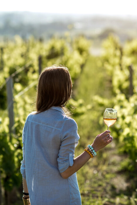 La route des vins Alsace : Une femme dans un vignoble, un verre de vin à la main.