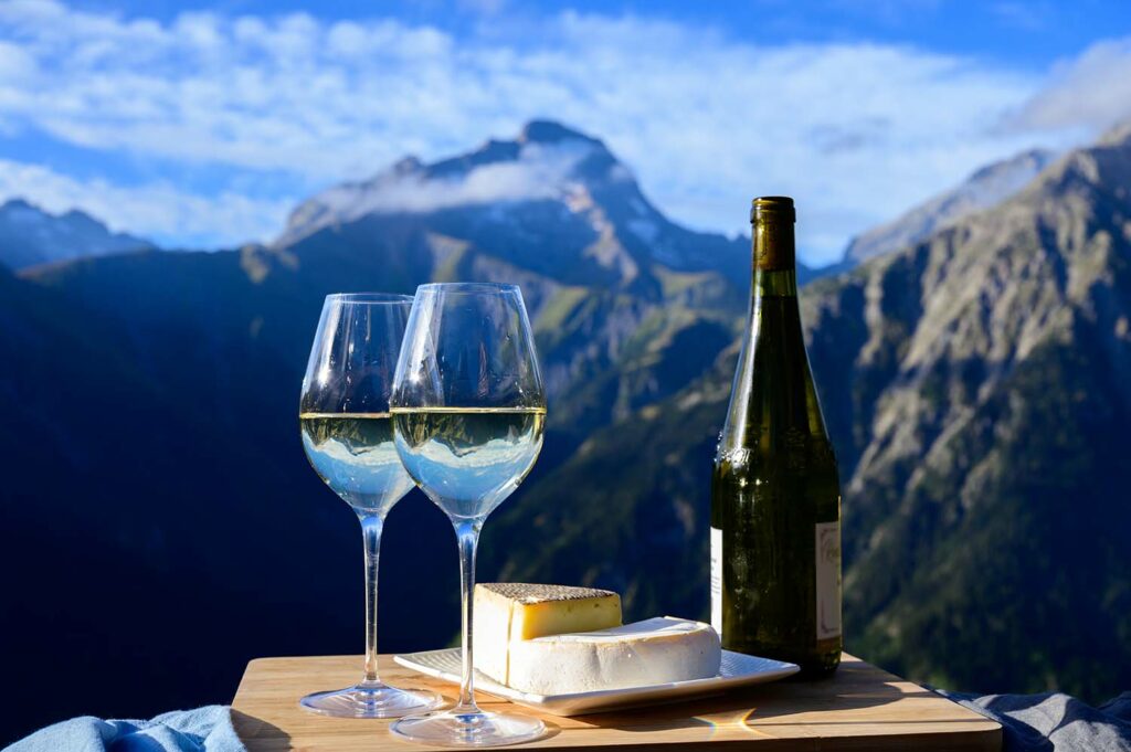 Spécialités savoyardes : vin blanc et fromage avec vue sur les montagnes savoyardes.