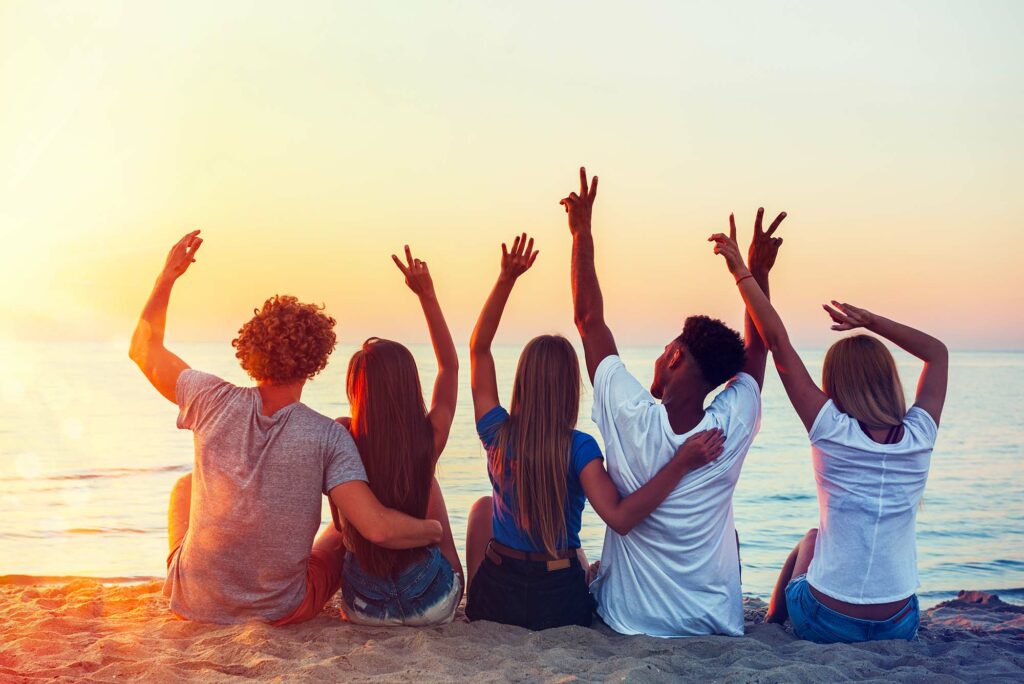 Voyage entre amis : un groupe d'amis sur la plage au coucher du soleil.