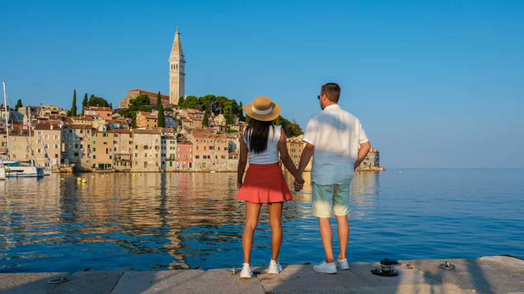 Couple amoureux regardant le coucher de soleil sur la mer, créant un moment romantique.