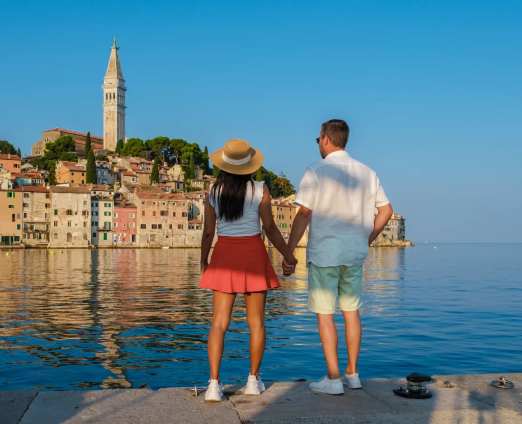 Couple amoureux regardant le coucher de soleil sur la mer, créant un moment romantique.