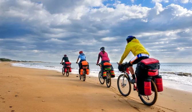 Famille en vacances zéro déchet se déplaçant à vélo sur une plage écoresponsable.