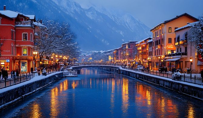 On a snowy winter evening, a lot of white snow is piled up near a city stream, houses and street lights are turned on, and many people are passing by on a snow-covered road.