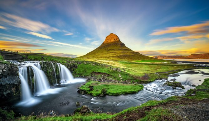 Summer sunset over the famous Kirkjufellsfoss Waterfall with Kirkjufell mountain in the background in Iceland. Long exposure.