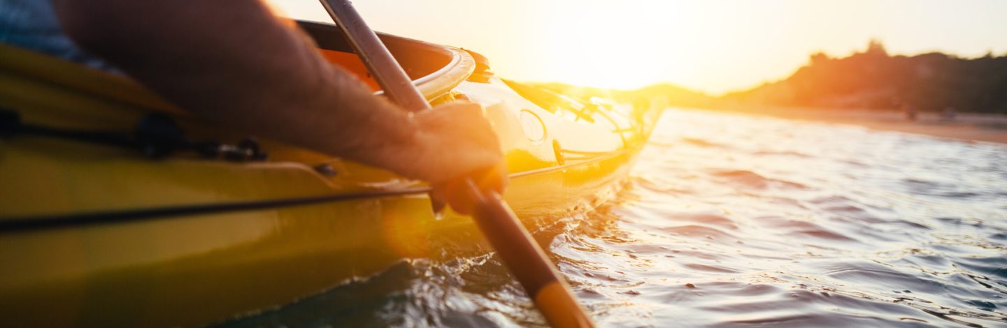 Close up of man holding kayak paddle at sunset