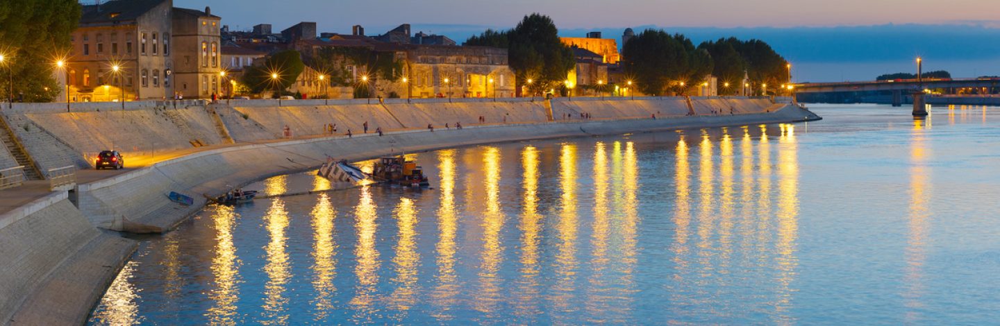 People walking at an embankment of Arles, France at twilight