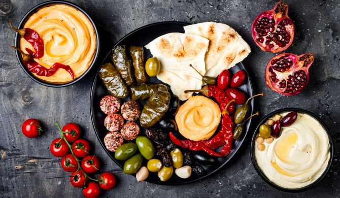 Arabic traditional cuisine. Middle Eastern meze platter with pita, olives, hummus, stuffed dolma, labneh cheese balls in spices. Mediterranean appetizer party idea