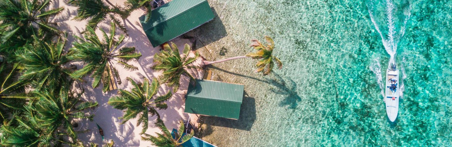 Aerial drone view of Tobacco Caye small Caribbean island with palm trees and bungalows in the Belize Barrier Reef