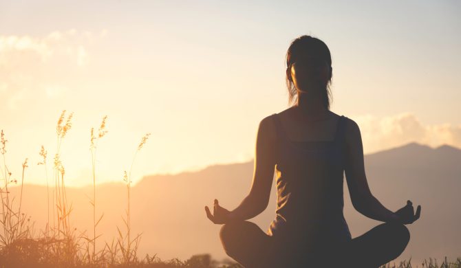 silhouette fitness girl practicing yoga on mountain with sun light