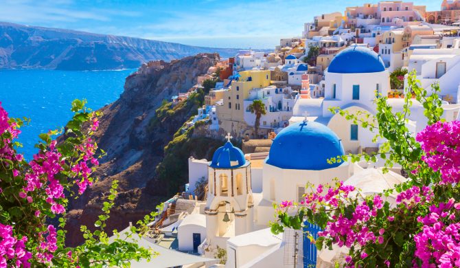 Santorini island, Greece. Oia town traditional white houses and churches with blue domes over the Caldera, Aegean sea.