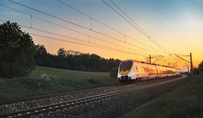 Modern regional train traveling with speed on railway tracks through nature landscape, at sunset, near Schwabisch Hall, Germany.