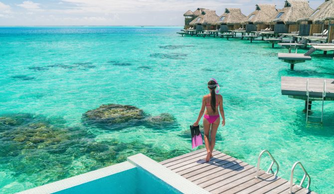 Luxury overwater bungalows Tahiti resort woman going snorkeling from private hotel room on Bora Bora island, French Polynesia. Travel vacation recreational activity watersport fun leisure.