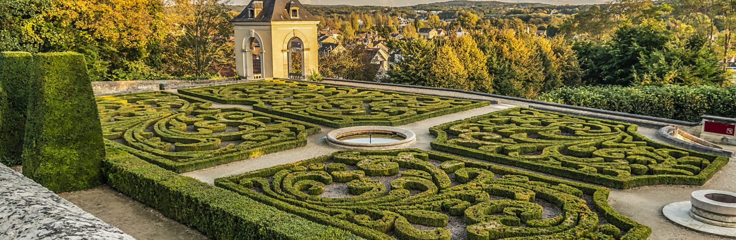 Small lovely public garden at the foot of 17th century Chateau d’Auvers sur Oise at sunset. Auvers-sur-Oise (27.2 km from Paris), France.