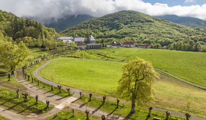 Vue panoramique des Pyrénées depuis un sentier de randonnée, avec montagnes et vallées verdoyantes.