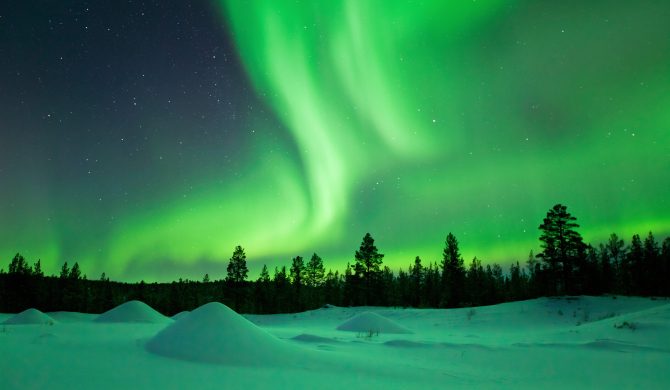 Spectacular aurora borealis (northern lights) over a snowy winter landscape in Finnish Lapland.