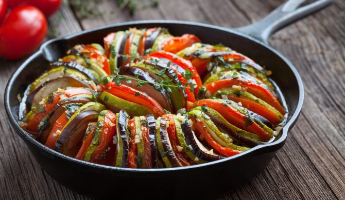 Traditional homemade vegetable ratatouille baked in cast iron frying pan healthy diet french vegetarian food on vintage wooden table background. Rustic style