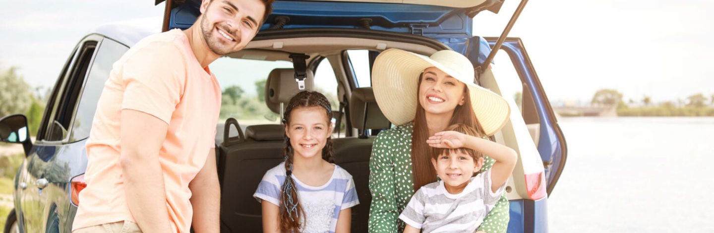 Checklist voyage : une famille assise dans le coffre de la voiture