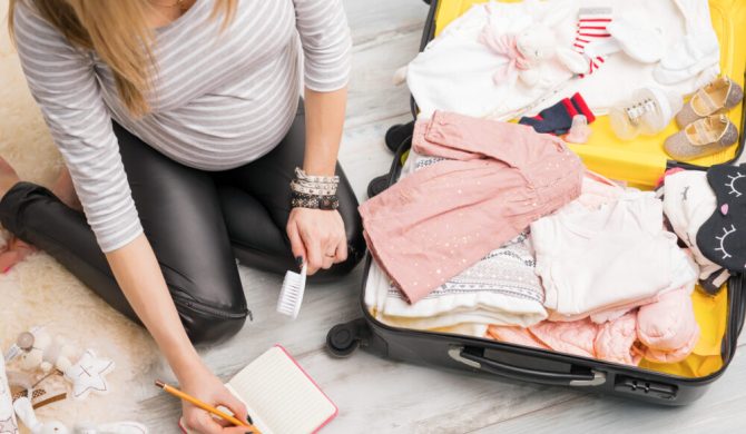 Checklist voyage : une femme prépare la valise de son enfant, en prenant des notes sur un carnet