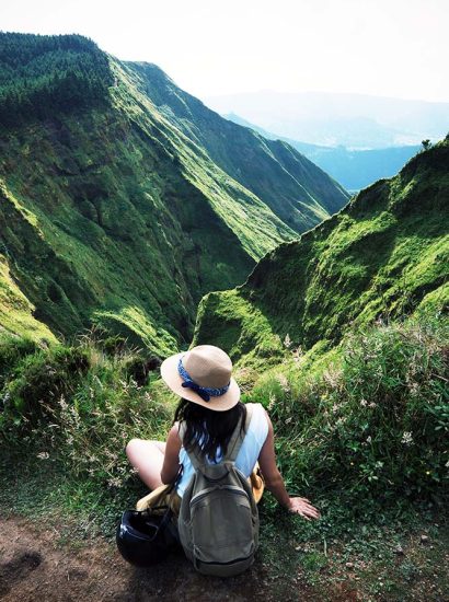 Slow tourisme : une femme comtemple le paysage verdoyant des montagnes