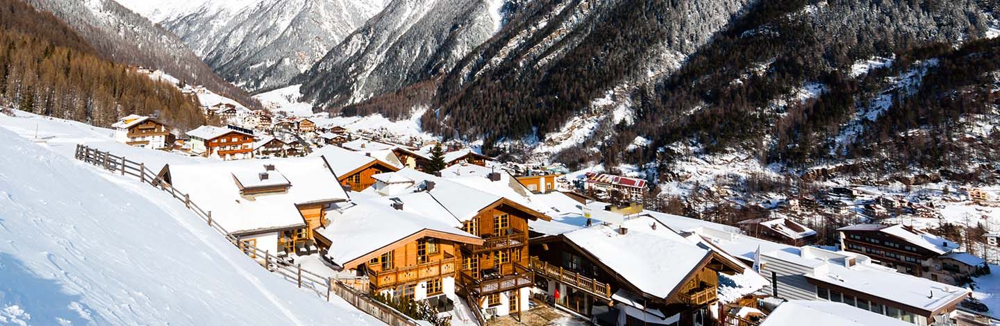 Stations de ski écoresponsables : Un paysage en montagnes avec des chalets en contrebas.