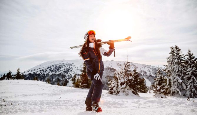 Stations de ski écoresponsables : une femme souriante, ses skis à la main