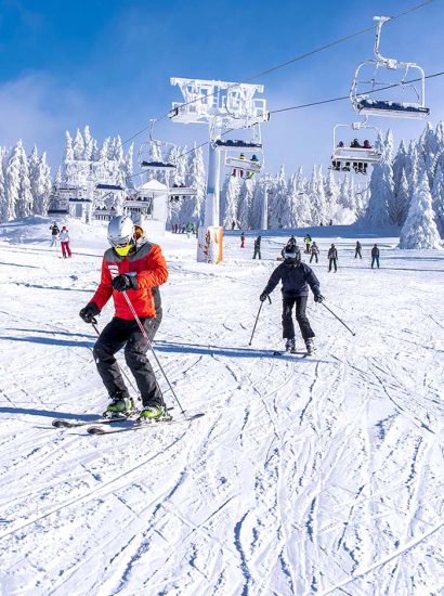Stations ski écoresponsables : deux personnes qui skient en dessous d'une remontée mécanique